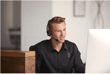 Customer service representative wearing a headset and working on a computer.