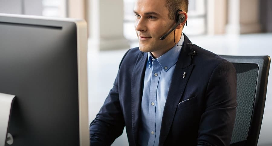 Man in a headset working at a computer in an office setting.