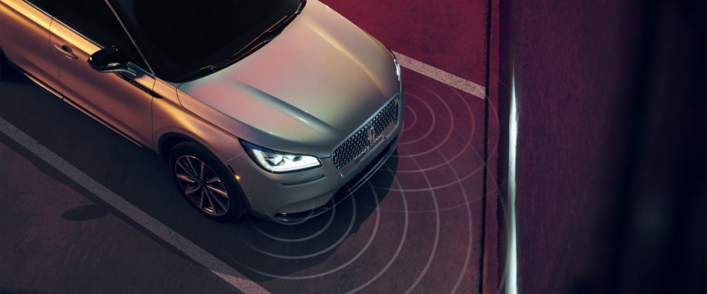 Top view of a silver car with active parking sensors, showing proximity detection in a parking space.