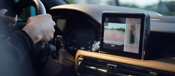 Driver using a car's rearview camera system, displayed on a dashboard screen.