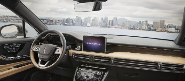 Car interior with luxurious dashboard, touchscreen display, and scenic city skyline view through the windshield.
