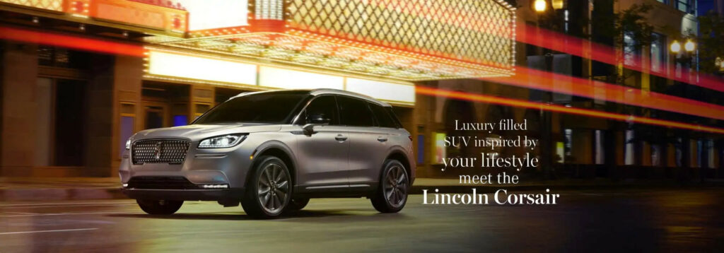 Silver Lincoln Corsair SUV driving at night with city lights and branding text about luxury.