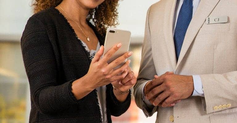 Two professionals discussing over a smartphone; one wears a suit with a name tag.