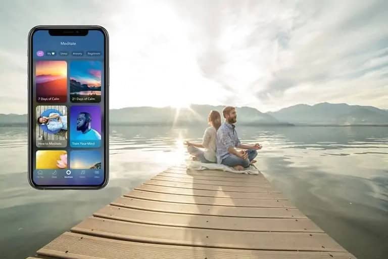 A couple meditating on a dock by a serene lake, with a smartphone showing a meditation app.