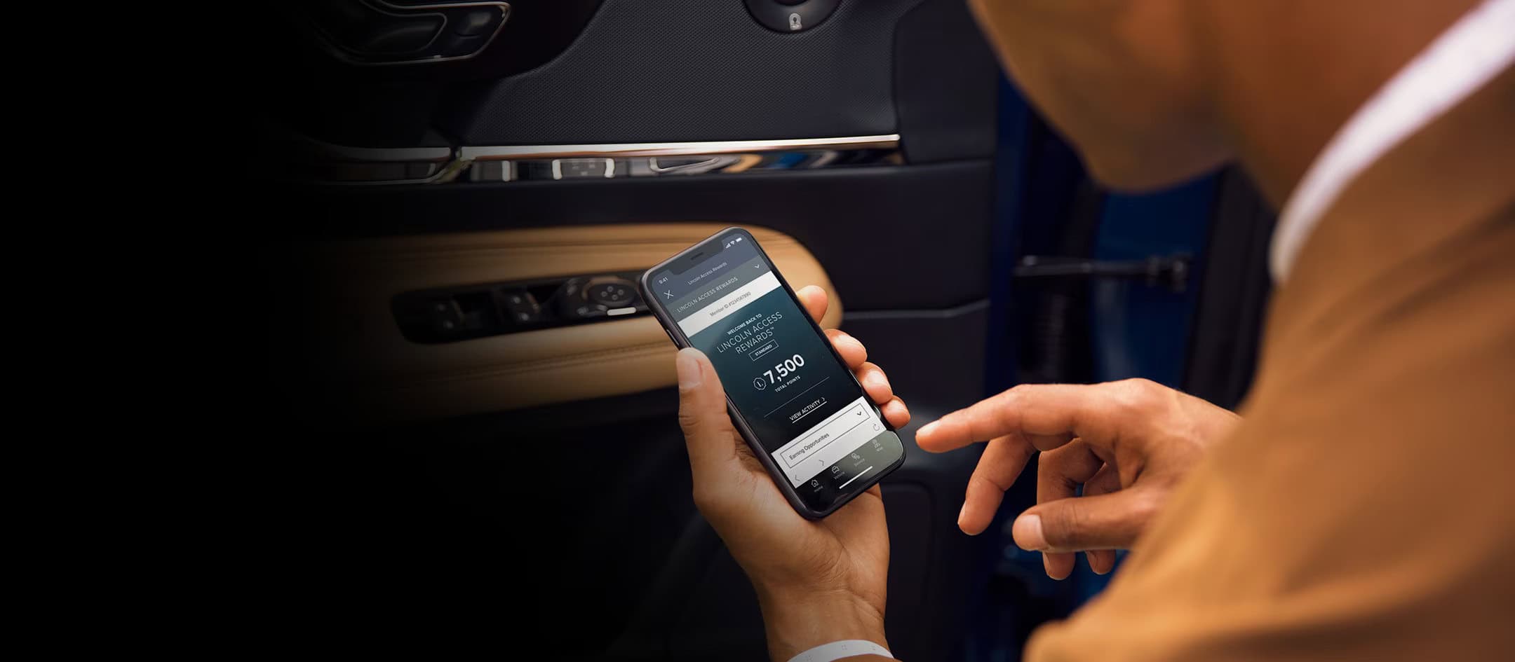Person in a car using a smartphone app showing Lincoln Access Rewards with 7,500 points.