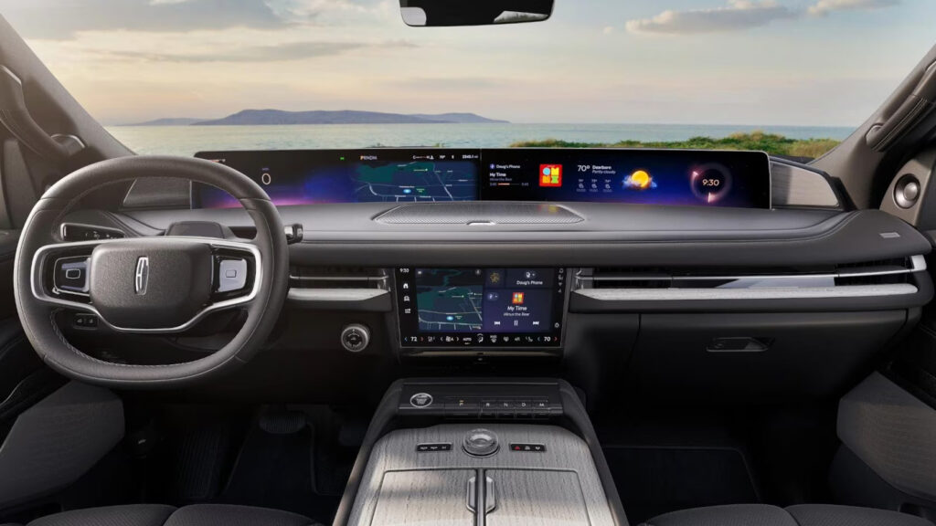 Luxurious car interior showcasing a sleek dashboard with digital displays and a scenic ocean view.